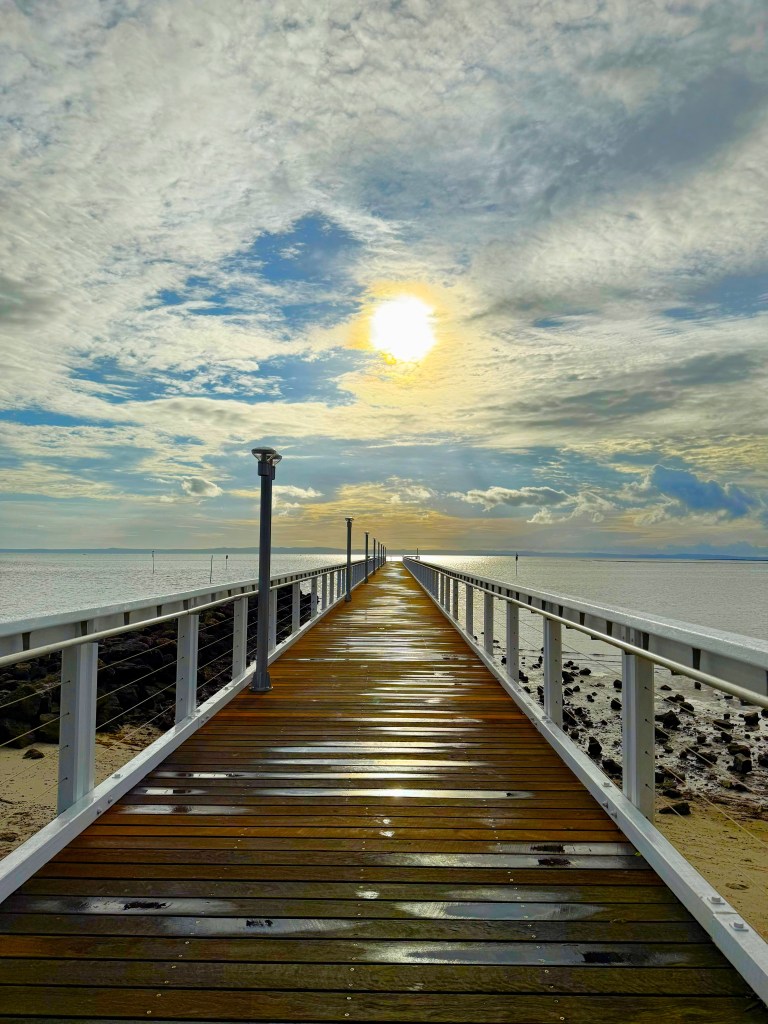 Wellington Point Jetty. Wooden jetty over the sea with the morning sun rising above it.