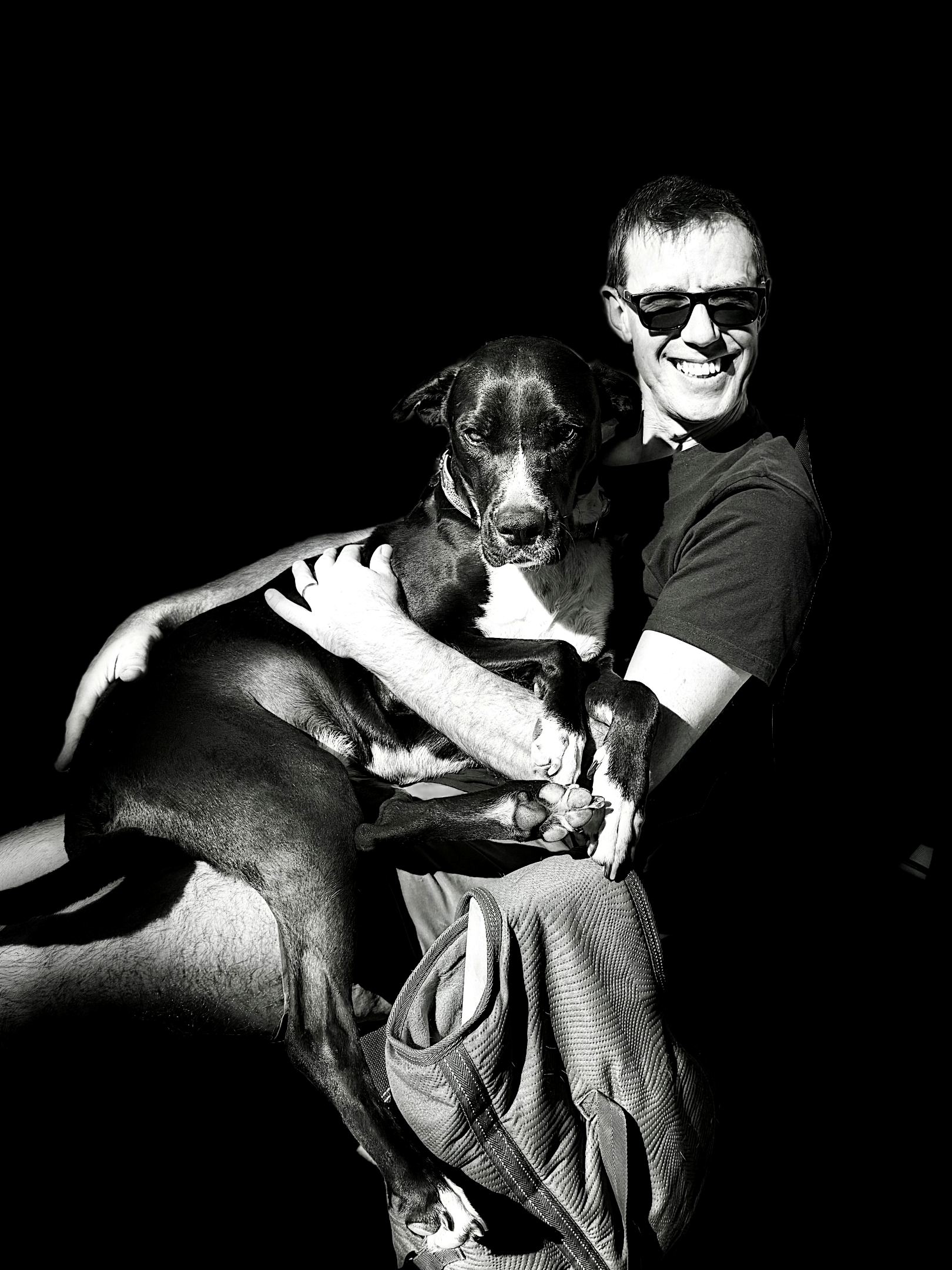 A man with a big black dog on his lap.