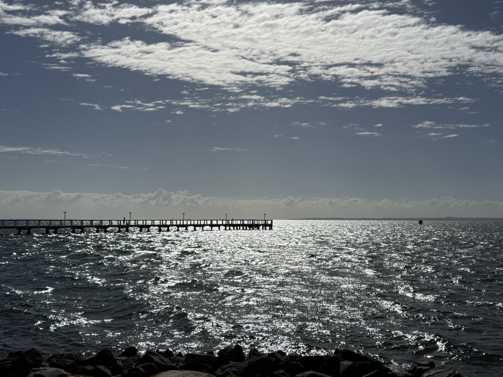A pier out to sea in silhouette.